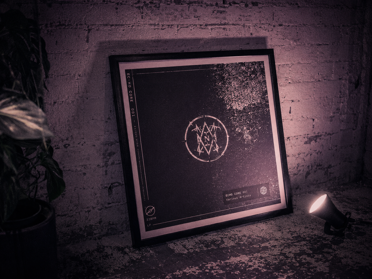 Finished album artwork in simple frame leaned against brick wall, abstract piece, small spotlight, theatrical mauve gel cast